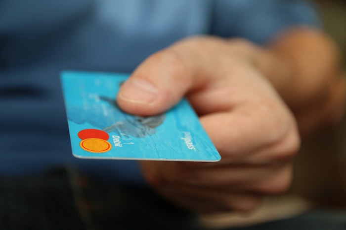 A blue credit card in the foreground of a photo.
